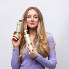 En kvinna med långt, blont hår håller upp två flaskor från Bobb's Hair Care. Hon har tunt hår och hoppas på att dessa produkter ska hjälpa.