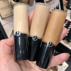 En hand håller tre flaskor Giorgio Armani foundation i olika nyanser.