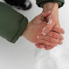 Två händer gnids mot varandra i snön, med synliga spår av torra handflator.