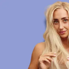 Blond kvinna med långt, tjockt hår som verkar ha hög porositet. Hon rör vid sitt hår med fingrarna.