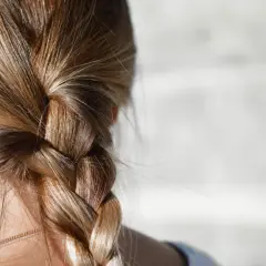 Närbild på en fläta med blont hår. Några små hårstrån som går av syns längs med flätan.