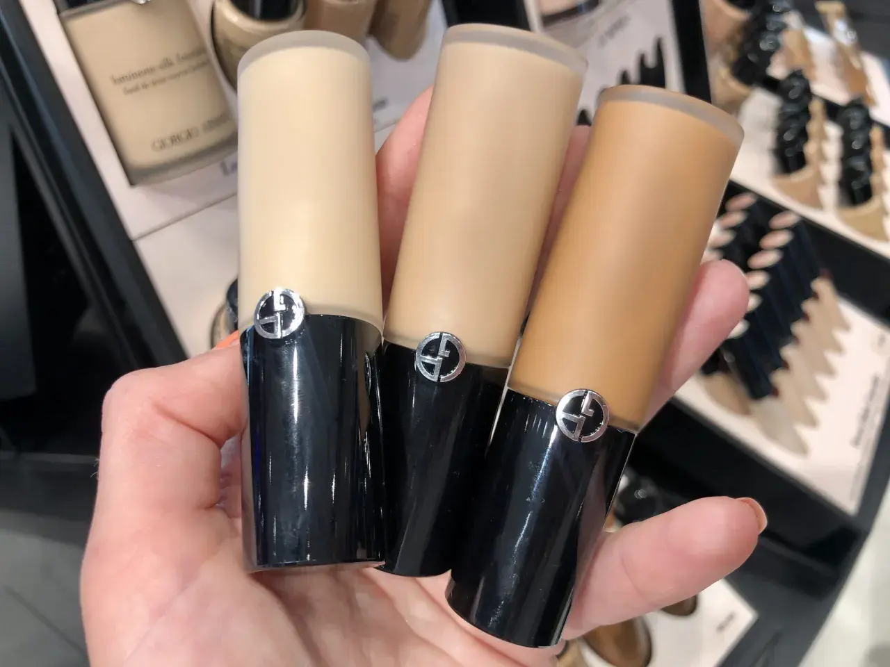 En hand håller tre flaskor Giorgio Armani foundation i olika nyanser.