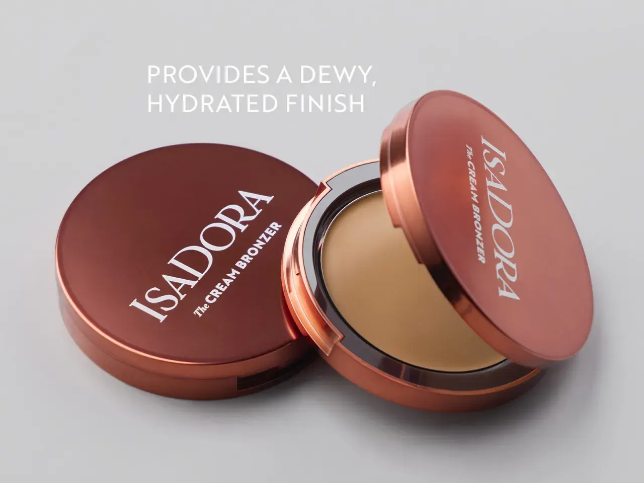 Två Isadora The Cream Bronzer-burkar, en öppen med krämig bronzer, ger en daggig, återfuktad finish.