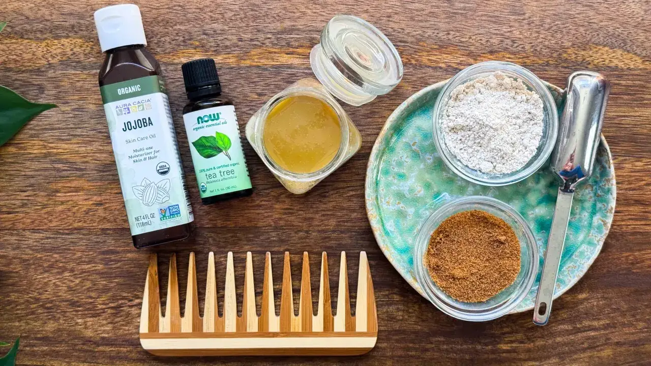 Ingredienser för hemmagjord hårbottenskrubb: jojobaolja, tea tree-olja, honung, havregryn och socker. En träkam ligger bredvid.