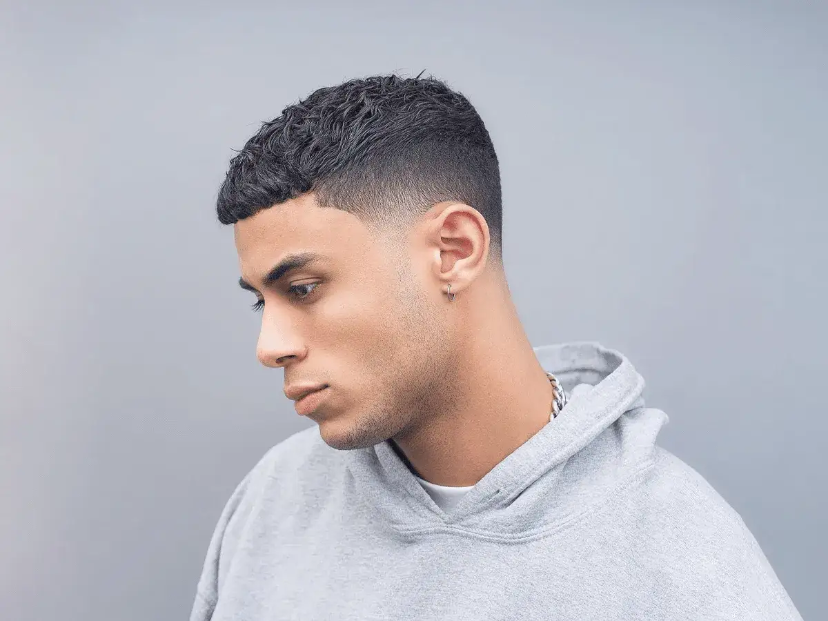Ung man med en snygg taper fade frisyr, kortklippt på sidorna och upptill.